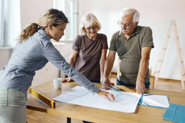 istock Senior couple and female architect analyzing blueprints. 1436329322