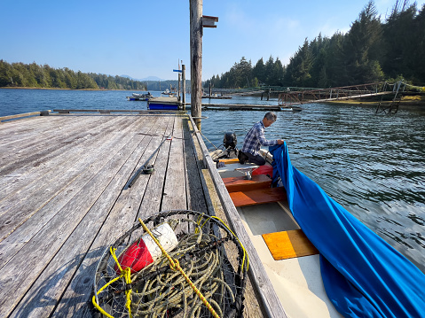An Asian senior man packs up at a dock after a day of crabbing and fishing. Bamfield, Vancouver Island, British Columbia, Canada.