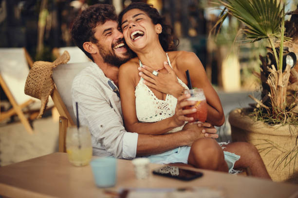 istock Cheerful couple laughing on a deck chair at the beach. 1436330898