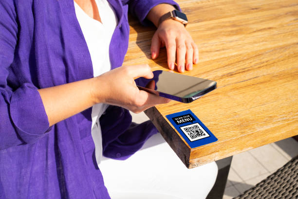 Woman scanning QR code in bar with mobile phone for online menu stock photo