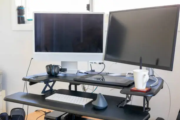 Modern dual monitor computer at a stand up desk in an office