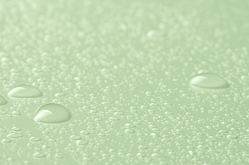 Drops of micellar water or cosmetic tonic on a green background. Closeup, macro photography.