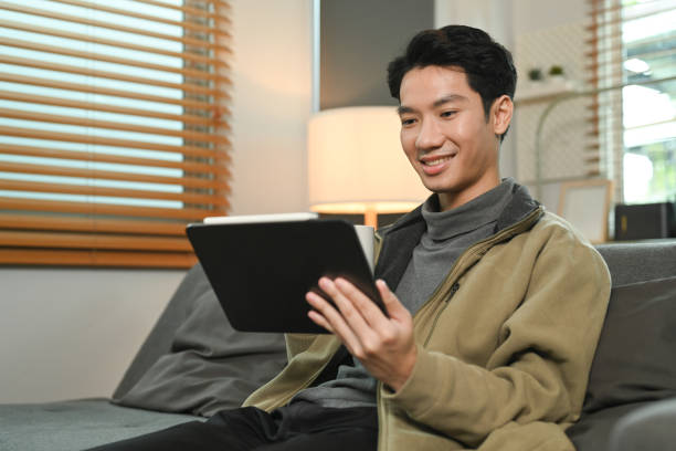 istock Smiling man sitting on comfortable couch, enjoy browsing internet on laptop. People and technology concept. 1436334544