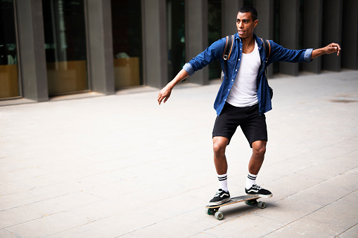 Young handsome man with skateboard. Happy African man having fun outside.