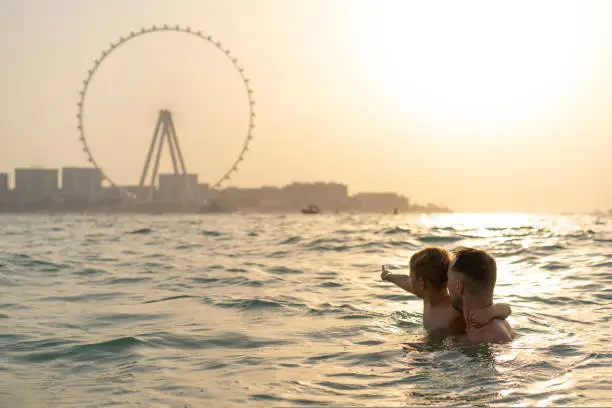 Photo of Dad and son swim in the sea with views of Dubai in the background