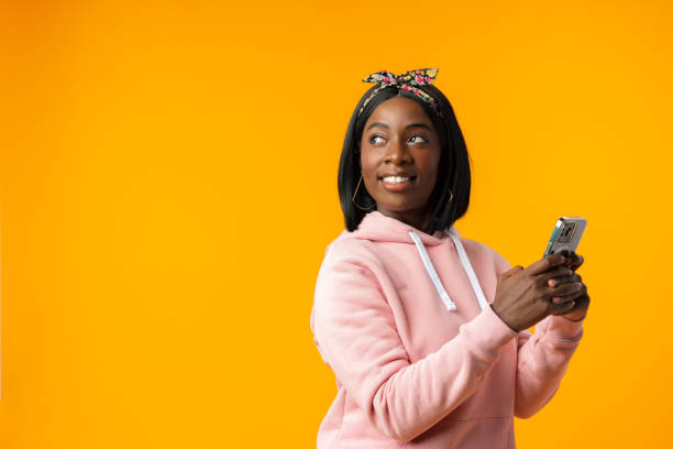 istock Happy african girl using her smartphone against yellow background. 1436342741