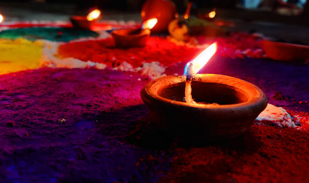 Tihar festival background. Diwali oil clay lamps with intricate design and glowing flame on multicolored rangoli background. Burning diya in the night. stock photo
