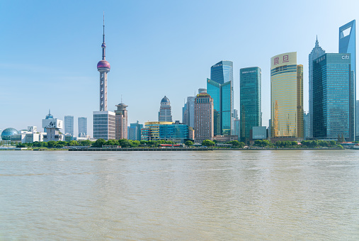 shanghai skyline in the morning, showing the Huangpu river with passing cargo ships, financial district and cloudy sky background