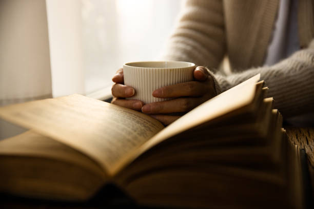 istock Woman hand holding coffee cup and reading a book 1436350253