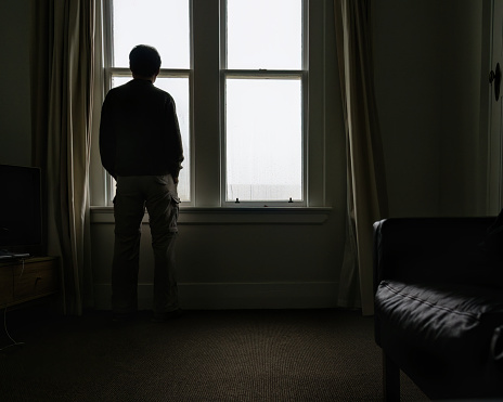 Man standing by the window with condensation, looking outside.