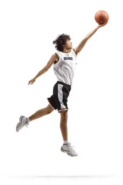 Full length shot of a basketball player performing a layup isolated on white background