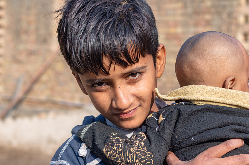 refugee boy carrying his new born brother