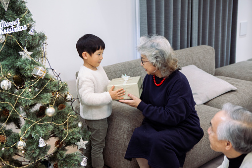 A three-generation family Christmas in Japan.\nLittle boy happy to receive a Christmas gift from his grandmother.