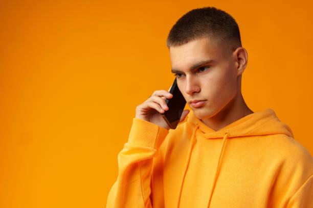 istock Handsome young man talking on the phone on yellow background 1436357822