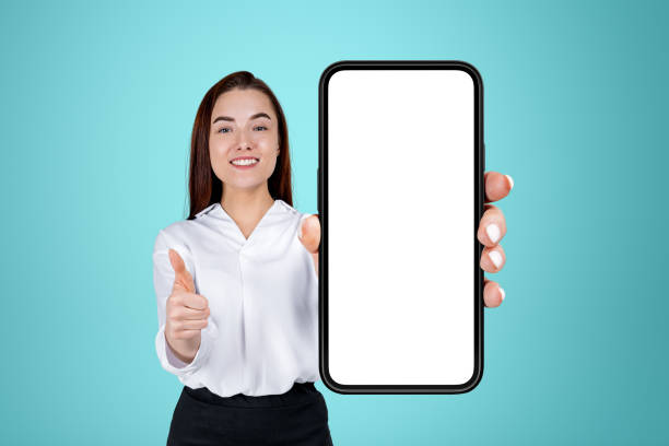 istock Businesswoman with thumb up, phone empty display on blue background 1436360046