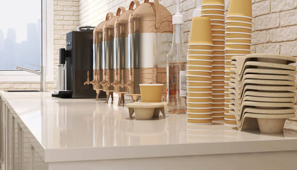 Close up catering beverage station counter top with espresso coffee making machine and stainless steel hot drink dispensers, syrup, paper cup and snack holder tray