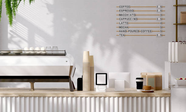 Modern and luxury design of cafe counter with wooden top, espresso machine, digital tablet computer cash register with sunlight and leaf shadow from window on white wall Modern and luxury design of cafe counter with wooden top, espresso machine, digital tablet computer cash register, stack of paper coffee cups with sunlight and leaf shadow from window on white wall booth design stock pictures, royalty-free photos & images