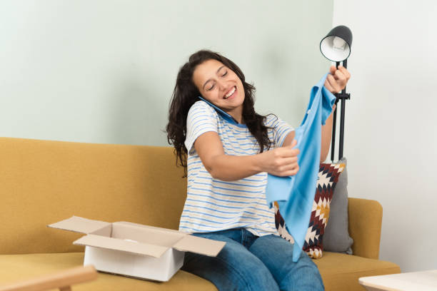 istock Young woman talking on the phone while opening a gift she's got 1436362739