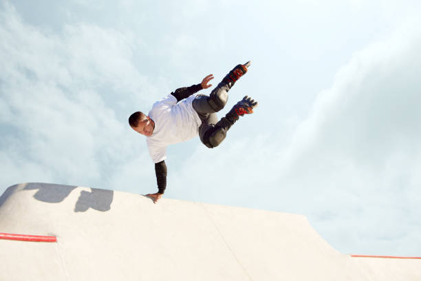 istock Energetic man on roller skates in motion at modern roller skate park. Roller skater doing dangerous and daring tricks. Sport, health, speed, and energy 1436364258
