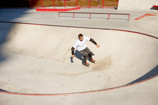 istock Energetic man on roller skates in motion at modern roller skate park. Roller skater doing dangerous and daring tricks. Sport, health, speed, and energy 1436364296