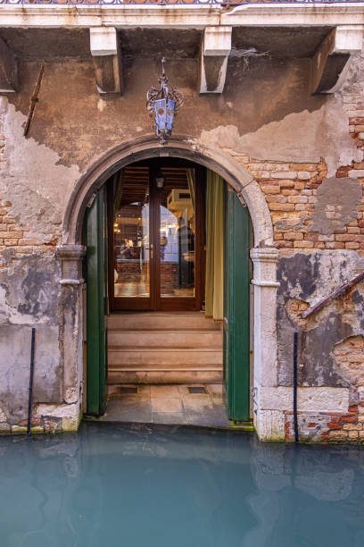 Doorway in a old and weathered brownstone wall facing a canal in the center of the old and famous Italian city Venice