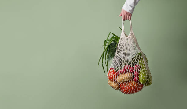 istock Mesh bag with vegetables and herbs in female hand. 1436366630