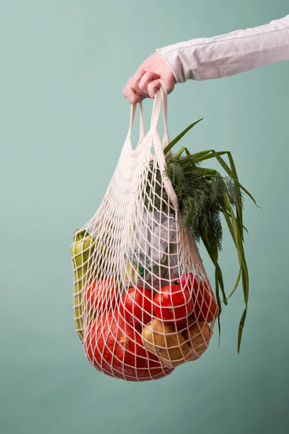 istock Mesh bag with vegetables and herbs in female hand. 1436366671