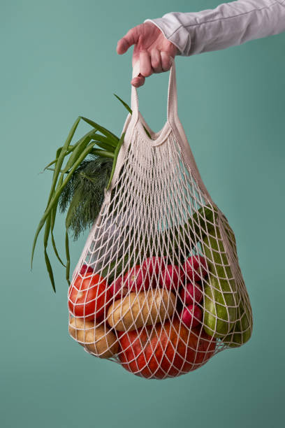 istock Mesh bag with vegetables and herbs in female hand. 1436366722