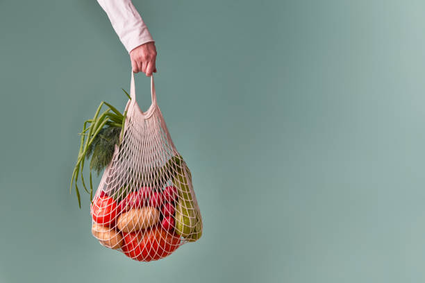 istock Mesh bag with vegetables and herbs in female hand. 1436366776