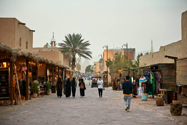 Wide angle view at dusk of male and female locals and tourists visiting cafes and market bazaar shopping area for traditional crafts by local artisans.