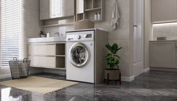 Modern and luxury design of beige laundry room with washing machine, counter, cabinet, shelf connected to kitchen on black granite tile floor with sunlight from window blinds stock photo