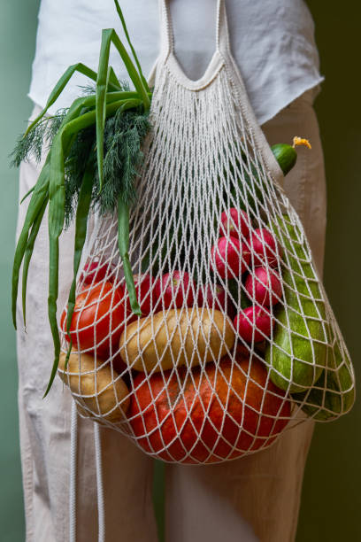 istock Woman hold mesh bag with vegetables and herbs. 1436367989