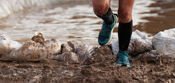 Participant in an obstacle course race runs out of a water obstacle, concept of hardness and effort