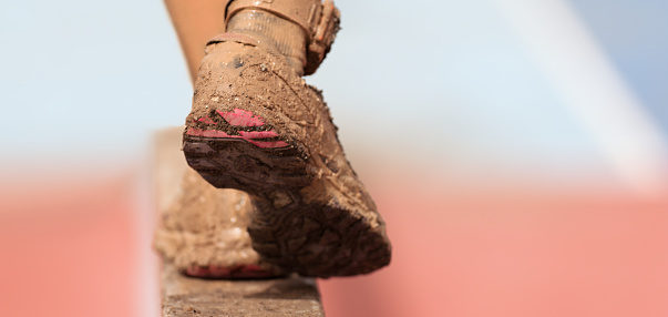 Mud race runners. Participant walking on the obstacle, catches balance