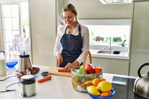 istock Young blonde woman smiling confident cutting carrot at kitchen 1436371126