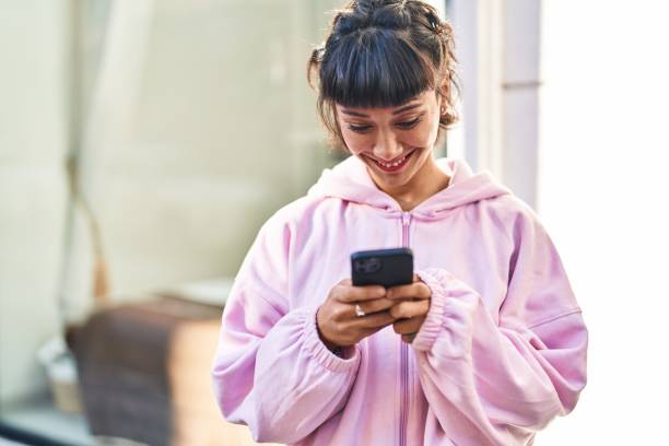 istock Young woman smiling confident using smartphone at street 1436373308