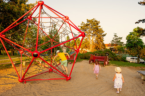 Kids play in rope polyhedron climb at playground outdoor.