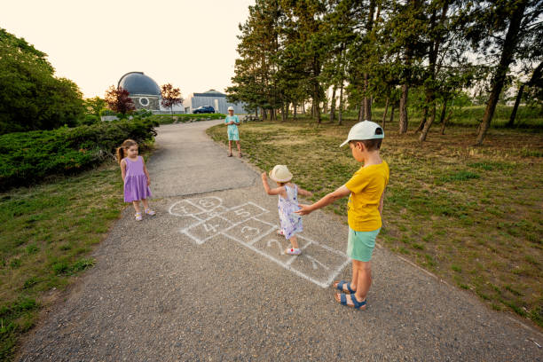 niños jugando rayuela en el parque. actividades al aire libre para niños. - little girls sidewalk child chalk fotografías e imágenes de stock