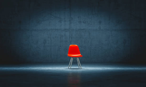 sedia rossa solitaria in una stanza di cemento. - foto stock