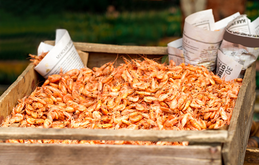 Heap of pink shrimps in wooden box for sale on fish market