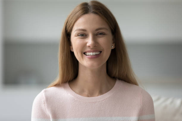 istock Headshot happy beautiful woman sit on sofa staring at camera 1436376595