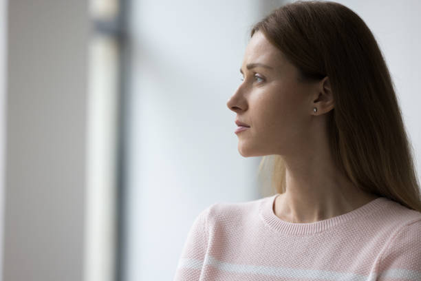 istock Side view sad woman staring into distance standing alone indoor 1436376610