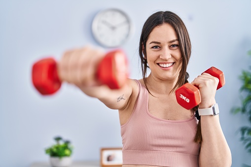 Young woman smiling confident training boxing exercise using dumbbells at home