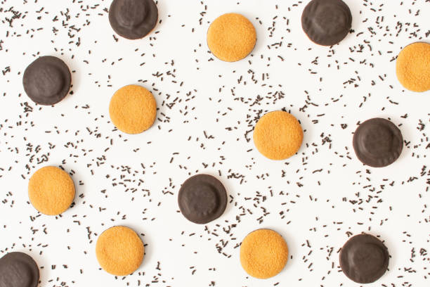 istock Sweet pattern made with chocolate cookies and chocolate sprinkles on white background. Chaotic flat lay. Process of making birthday cheesecake. 1436380849