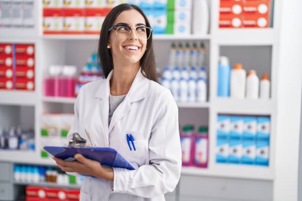 istock Young beautiful hispanic woman pharmacist writing on document at pharmacy 1436381158