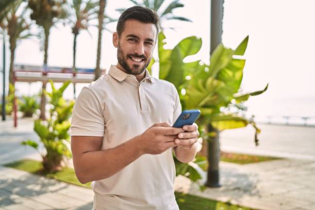 istock Young hispanic man smiling confident using smartphone at street 1436381551
