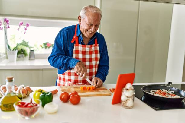 istock Senior man smiling confident cooking and watching online recipe at kitchen 1436384080