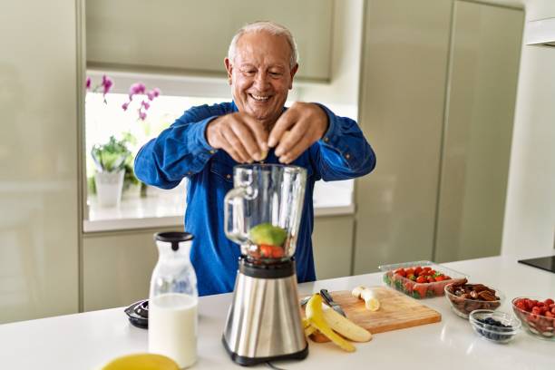 istock Senior man smiling confident putting banana in blender at kitchen 1436384089