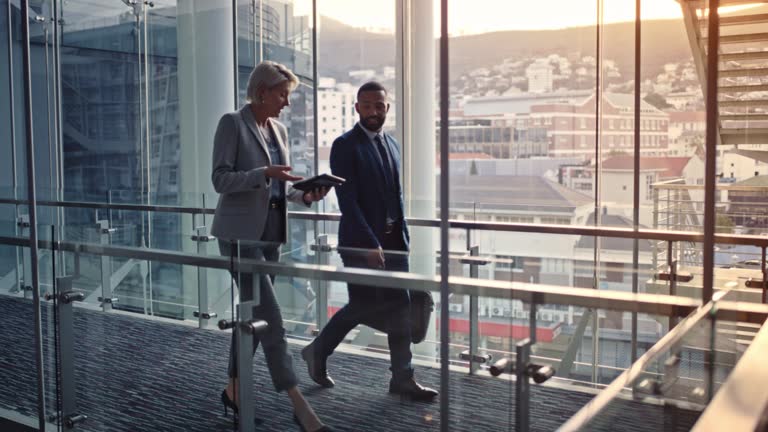 Business people, collaboration and teamwork with tablet in office for walking man and woman planning corporate strategy. Happy employees with smile, travel or conference vision on digital technology