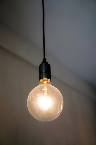 Old light bulb hanging on ceiling with copy space